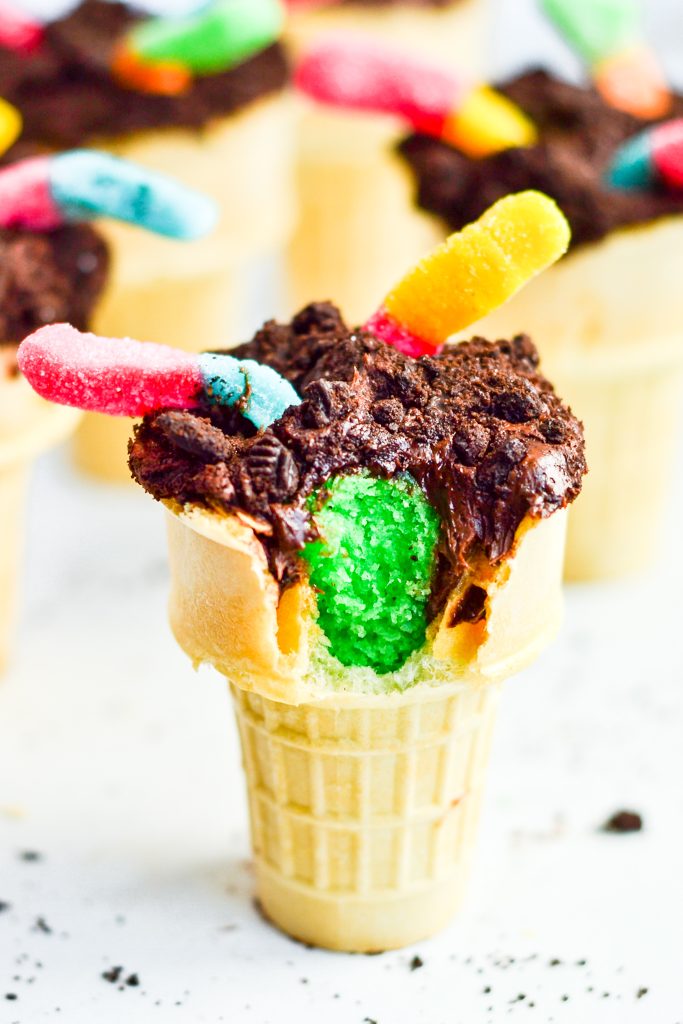 green cake in cone topped with frosting and worms