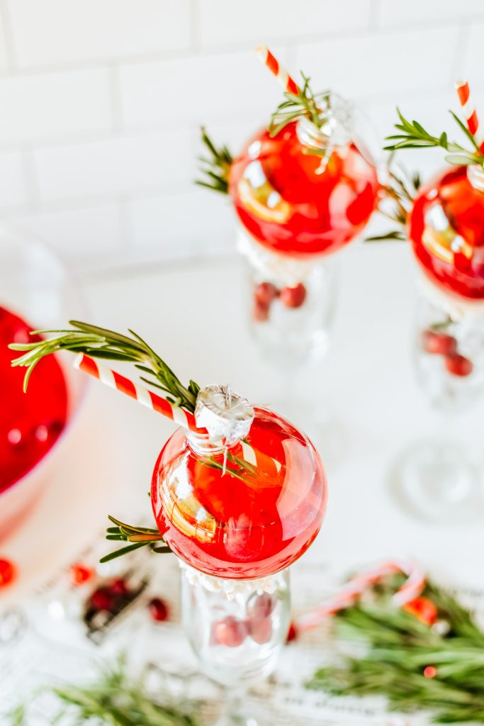 ornaments filled with red punch garnished with rosemary sprigs